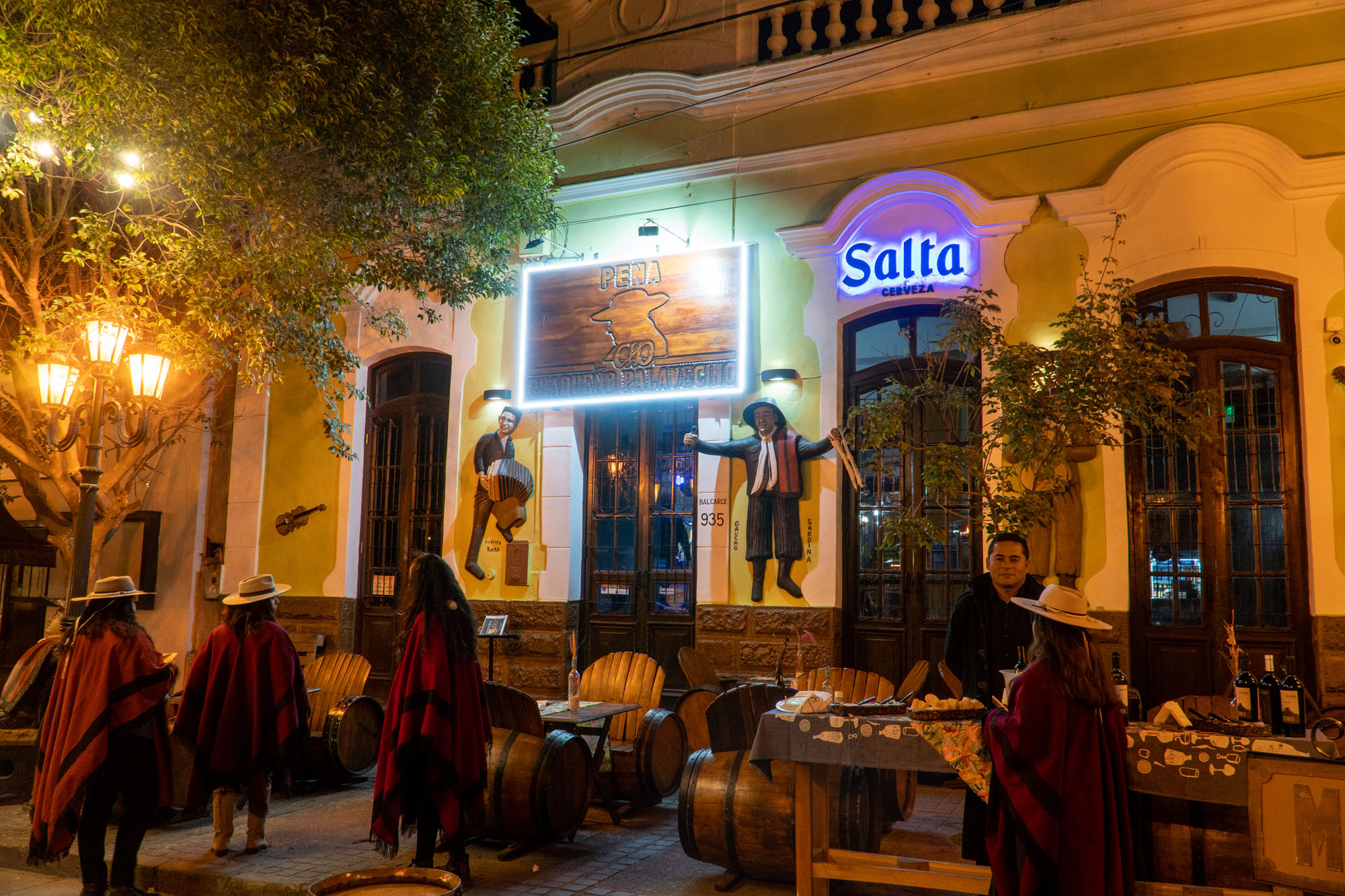 Peña salteña de noche con músicos y ponchos rojos